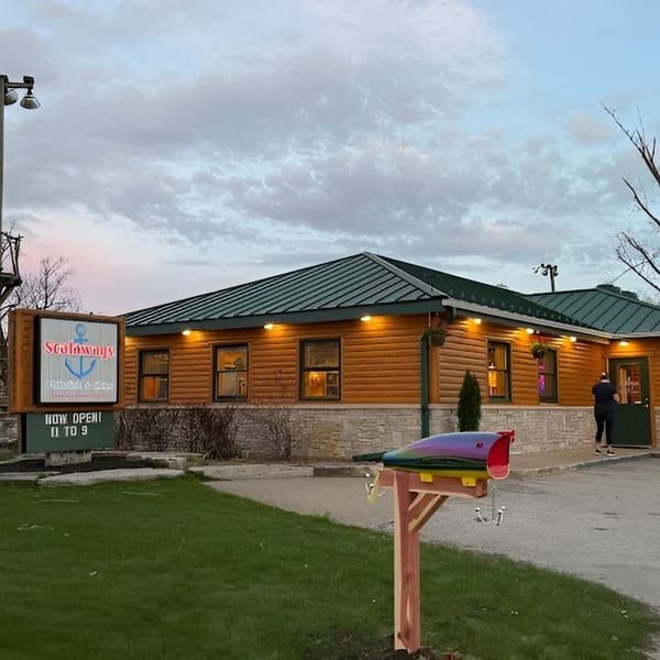Exterior of Scalawags restaurant at dusk, with a lit sign and a person entering the building.