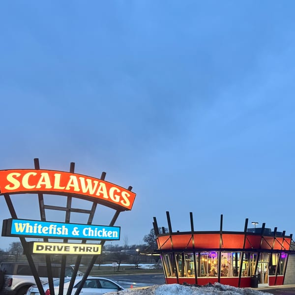 Scalawags restaurant sign and building at dusk, with "Whitefish & Chicken" and "Drive Thru" illuminated.