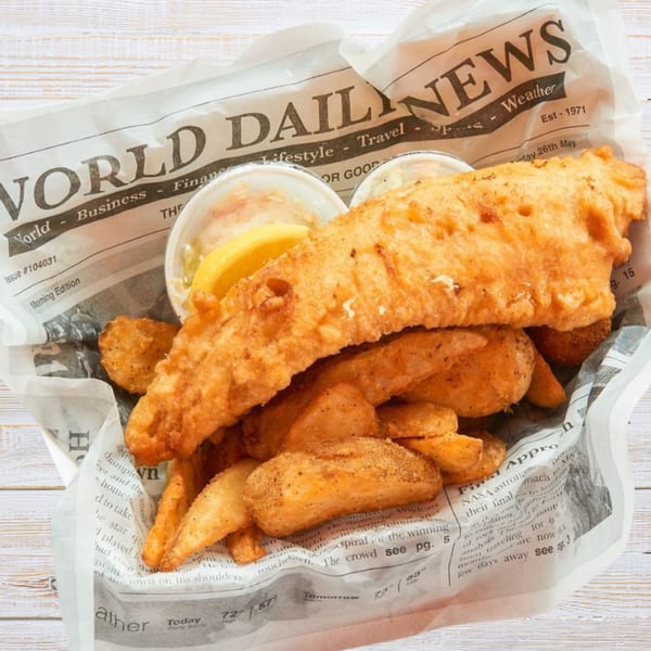 Crispy fish and chips served in newspaper, with lemon and tartar sauce.