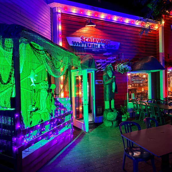 Scalawags Whitefish & Chips restaurant exterior at night, decorated with green and purple lights.