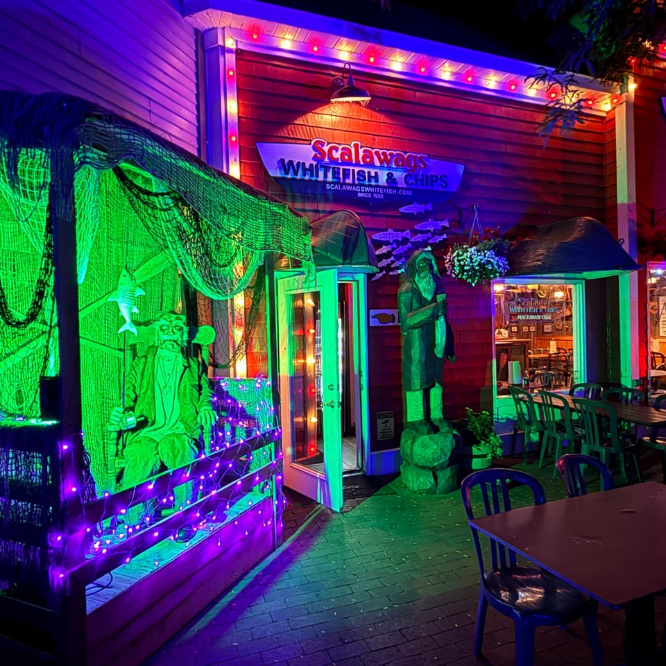 Scalawags Whitefish & Chips restaurant exterior at night, decorated with green and purple lights.
