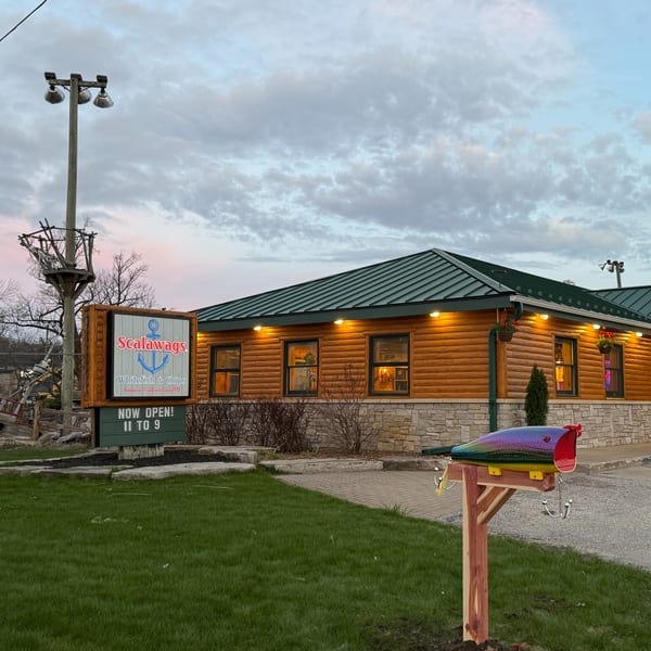Scalawags restaurant exterior with a log cabin facade, green roof, and a fish-shaped mailbox.