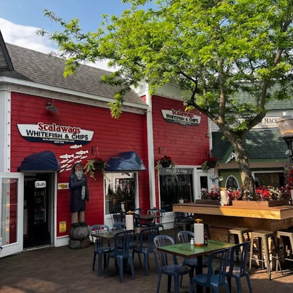 Scalawags Whitefish & Chips restaurant with red siding, outdoor seating, and a large tree.